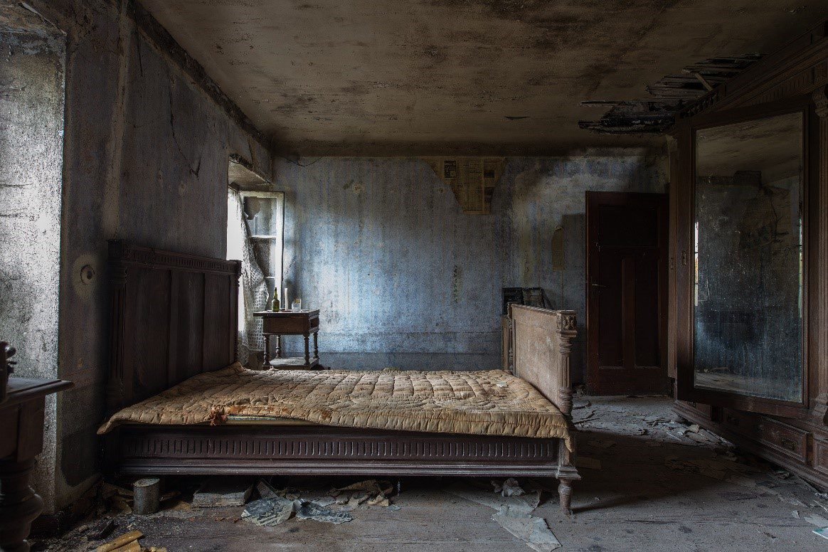 An empty room with an old mattress and bed