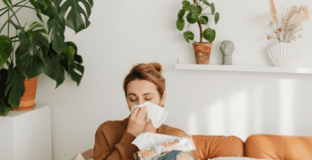 Woman sitting on a couch sneezing